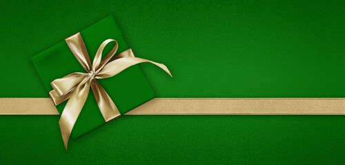 Blank gift greeting card with gift box present and bright shiny golden ribbon bow tape isolated on green background, top view and copy space, template for merry Christmas and St. Patrick day banner