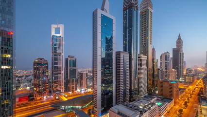 Aerial view of Dubai International Financial District with many skyscrapers night to day timelapse.