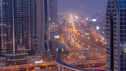 Fototapeta na wymiar Busy Sheikh Zayed Road aerial night to day timelapse, metro railway and modern skyscrapers around in luxury Dubai city.