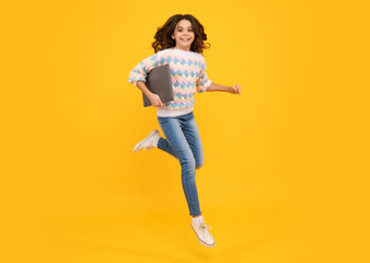 Smart girl with laptop in casual clothes isolated over yellow background. Run and jump, jumping kids.