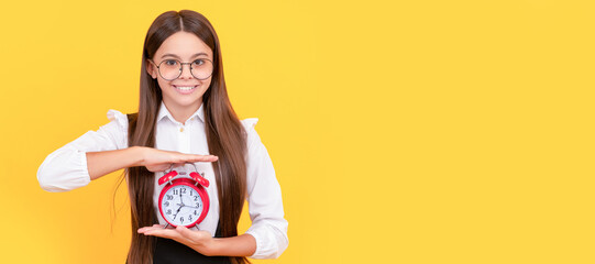 happy kid in school uniform and glasses with alarm clock showing time, school time. Teenager child...