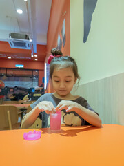 Obraz premium little girl playing with pink shiny slime on the table at the restaurant.