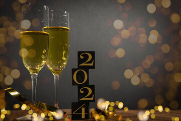 New Year New Year's Eve Sylvester celebration holiday greeting card background - Cubes with year 2024 and sparkling wine or champagne glasses on wooden table.