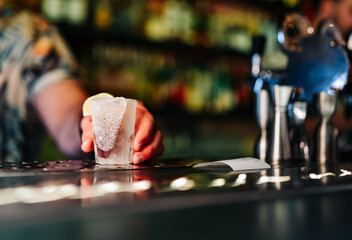 Bartender pouring tequila strong alcoholic drink into small shot glass
