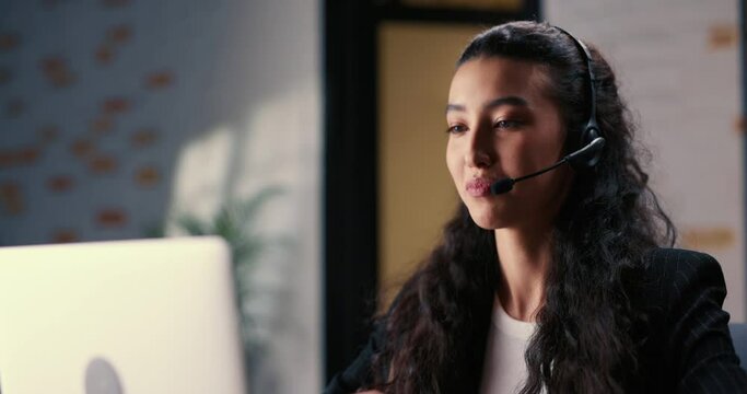 Female online consultant ends a conversation with her last client, removes her headphones and finally takes a break from her work. Woman tired of working in call center leans back in chair and rests.