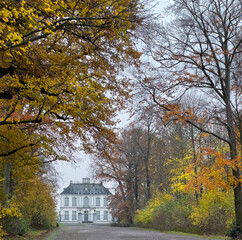 Beautiful stately white house surrounded by woods in full autumn colors.