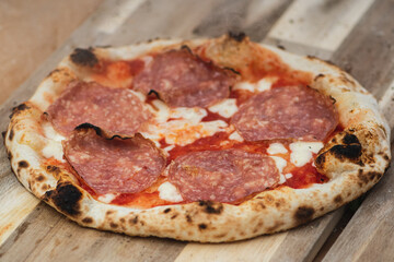 Hot pizza ready to eat with tomato sauce, mozzarella cheese and salami meat on a wooden board, with smoke