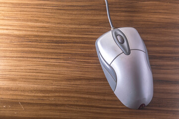 Modern computer mouse with wooden background and copy space