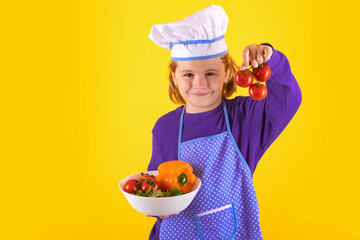 Kid cook hold tomato. Portrait of little child in uniform of cook. Chef boy isolated on studio background. Cute child to be a chef. Child dressed as a chef hat.