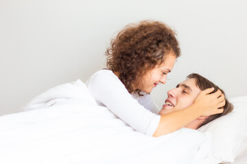 Obraz na płótnie Canvas Love couple lying on white bed in morning happy and carring together