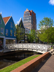 Naklejka premium Zaandam, Netherlands - April 26, 2022: Pedestrian Bridge over the water channel and traditional architecture of buildings in Zaandam, Netherlands