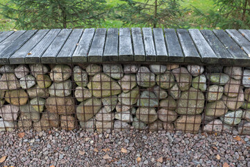 Modern garden bench around the fire pit made of gabion galvanized steel grid with granite stones