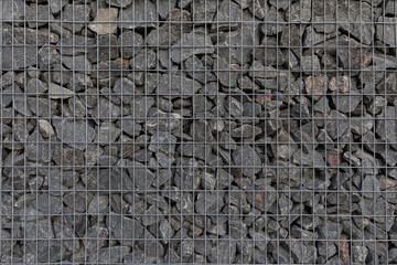 Modern privacy fence made of gabion galvanized steel grid with granite stones surrounding a residential building