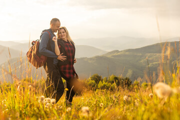 Happy traveler young couple resting in the mountains at sunset in spring or summer season.