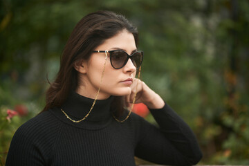 A confident and beautiful woman wears expensive sunglasses. Concept of luxury accesories for woman. Stylish brunette girl in the city