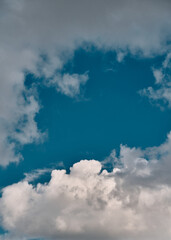 A piece of a blue sky with many clouds around. Midday cloudscape in the summer sky.