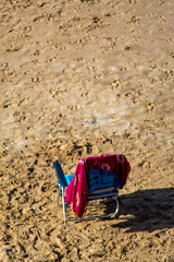 Hamaca abandonada en medio de la playa de Benidorm con el sol acariciándole rodeado de todas las pisadas en la arena de los turistas.