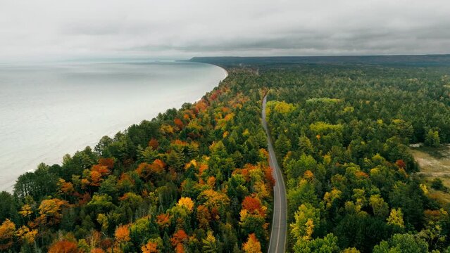 Aerial shot of a road running parallel to Lake superior in full fall color