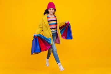 Fototapeta premium Funny teen girl hold shopping bag enjoying sale isolated on yellow. Portrait of teenager schoolgirl is ready to go shopping. Autumn shopping sale.