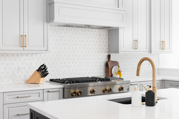 A detail shot of a beautiful kitchen's stainless steel luxury stove, hood, granite counter tops,...