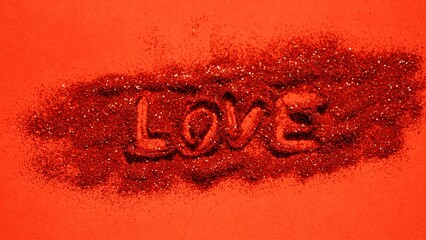 Red table with glittery sequins and finger drawn love text.