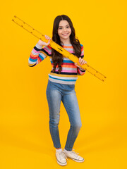 Fototapeta na wymiar School girl holding measure for geometry lesson, isolated on yellow background. Measuring equipment. Student study math. Happy teenager, positive and smiling emotions of teen schoolgirl.