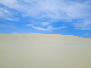 Fototapeta na wymiar Large white sand dune with blue sky and clouds in the background