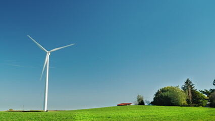 Fototapeta premium Idyllicistic landscape of a green meadow and a wind generator. Ecology and environment concept.