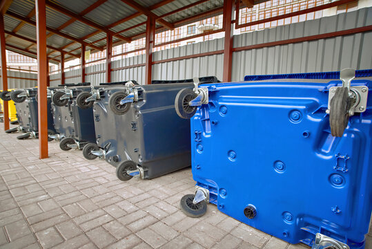 New colored plastic garbage bin for sorting various household waste. Colorful plastic bins for different waste under conopy next to new residential building. Place for dumpsters to collect garbage