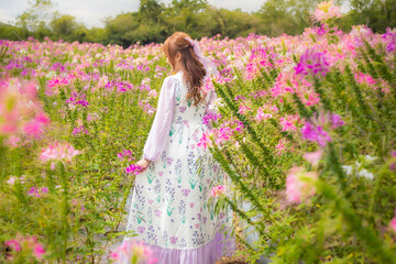 Fototapeta na wymiar woman wearing a long dress in a field of colorful flowers exudes a relaxed and freedom. Soft and select focus