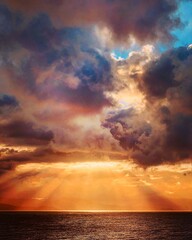Obraz na płótnie Canvas sun rays shining through the clouds over the ocean 