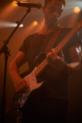 Music microphone, rock guitar and man playing electric instrument at metal band festival, dark...