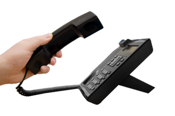 A man hand holds a phone near the monitors of office computers, isolated on a white background. Starting a telephone conversation at the workplace, close-up desk