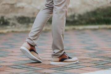 Close-up shot of a man wearing shoes with beige classic pants