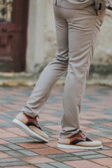 Vertical close-up shot of a man wearing sneakers with beige classic pants