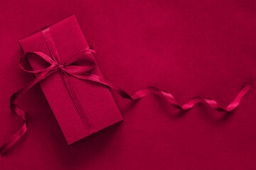 Present box with blue bow on viva magenta background. Festive concept. Color of the year 2023.
