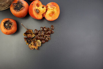 Pips and dried persimmon inflorescences on a gray background. Ripe juicy persimmon with bones. 