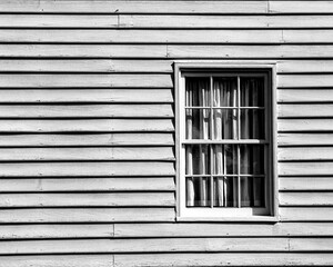 Closeup shot of a wooden house window with curtains, on a sunny day, in grayscale