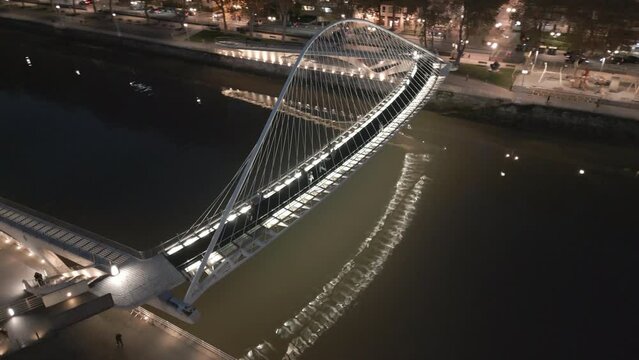 The Zubizuri bridge in Bilbao, at night, with its reflection on the river, and cityscape