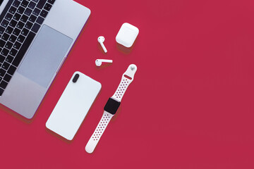 Desktop flat lay with laptop, mobile phone, wireless headphones and smart watches. Color of the year 2023: Viva magenta. Trendy colors concept, mockup with copy space