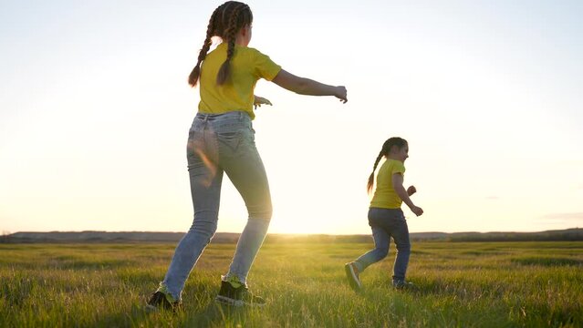 Happy active children run in park on green grass.Two girls play in nature at sunset.Summer recreation of children in park outdoors.Dream freedom outdoors.Concept of children happiness.Joyful smiles