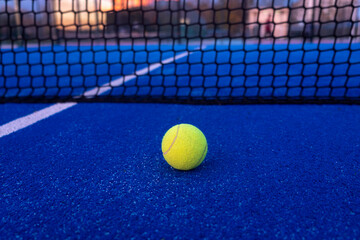 selective focus, a ball on a paddle tennis court at sunset. racket sports courts