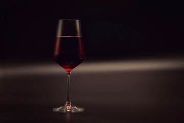 Glass of red wine. Grey and black stylish background.