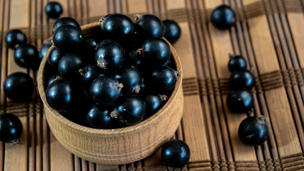 A pile of ripe blackcurrants. Blackcurrants in a wooden bowl
