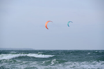 Kitesurfing, riding board waves during storm holding to flying kite.
