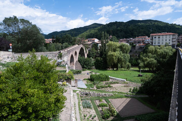 Sant Joan de les Abadesses, Spain - 23 August, 2022: Landscape of Old medieval bridge over the Ter river, people walking.