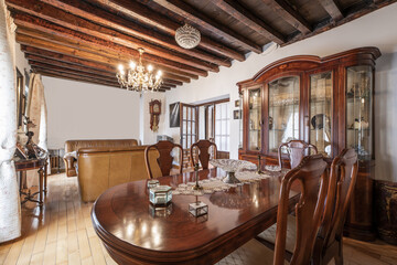 Living room with root wood dining table, sideboard with beveled glass doors and café au lait leather sofas with wood paneling