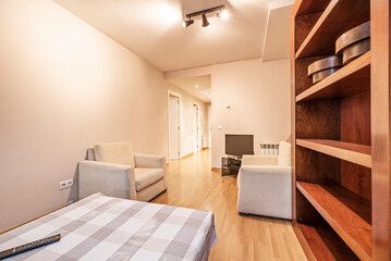 Living room with a wooden bookcase and a set of white fabric sofas and a square table with a tablecloth