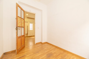 Empty room of a house with laminated oak wood flooring, smooth white painted walls and pine wood doors