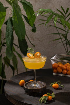 Glass of refreshing Kumquat & Thyme Vodka Cocktail served on dark wooden table surface
